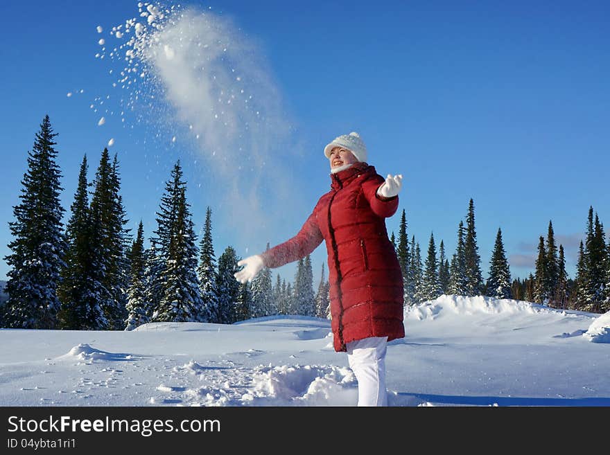 Girl clad in a red jacket, throws snow up on a sunny day of winter forest. Girl clad in a red jacket, throws snow up on a sunny day of winter forest.