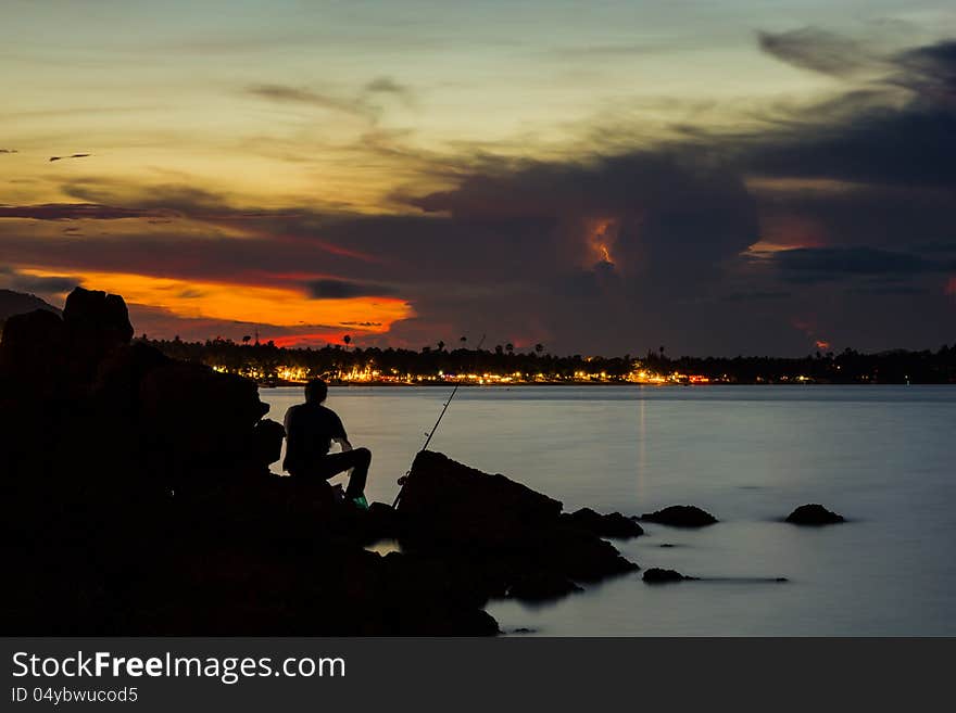 Silhouette fisherman catching a fish on sea