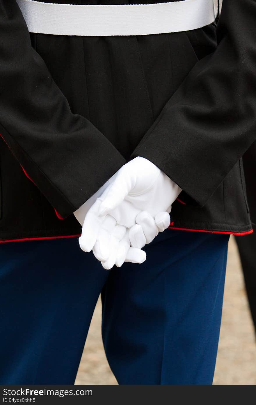 A marine soldier stands at attention during a wedding ceremony with his hands behind his back wearing full uniform and white gloves. A marine soldier stands at attention during a wedding ceremony with his hands behind his back wearing full uniform and white gloves.