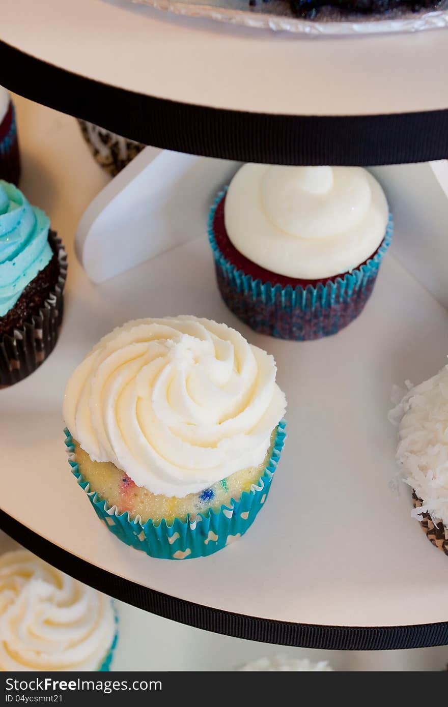 Several cupcakes on a serving table at a wedding ceremony and reception. The colors here are black, blue, and white. Several cupcakes on a serving table at a wedding ceremony and reception. The colors here are black, blue, and white.