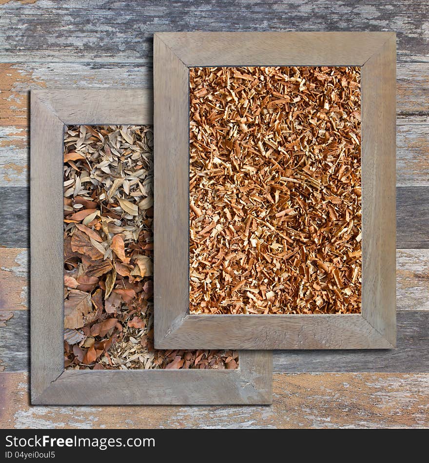 Sawdust and dry leaves in a wooden frame on a wooden background. Sawdust and dry leaves in a wooden frame on a wooden background.