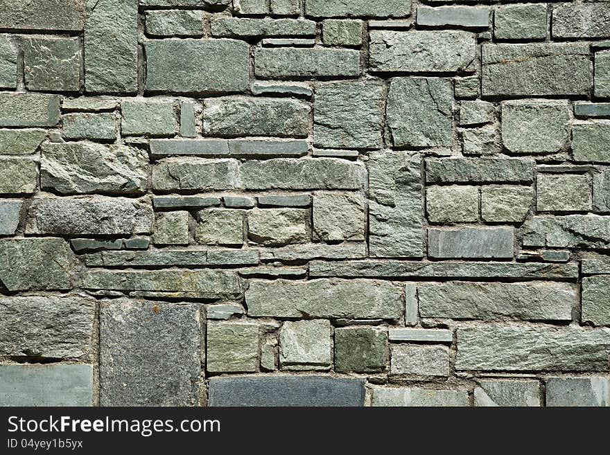 Abstract architectural background with a cut stone wall of irregular rectangular blocks with a rough textured surface