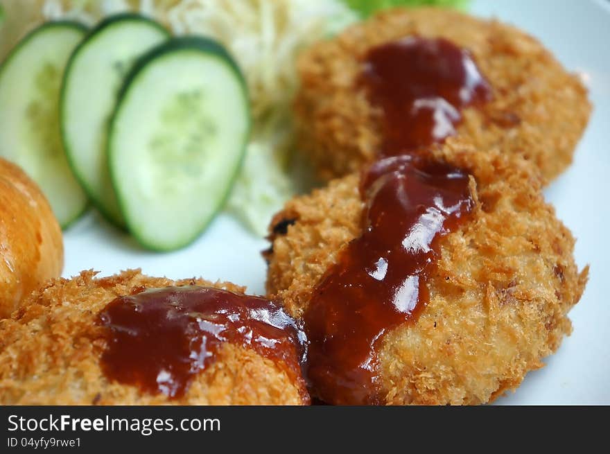 Fried chicken nuggets with tomato sauce and slice of cucumber