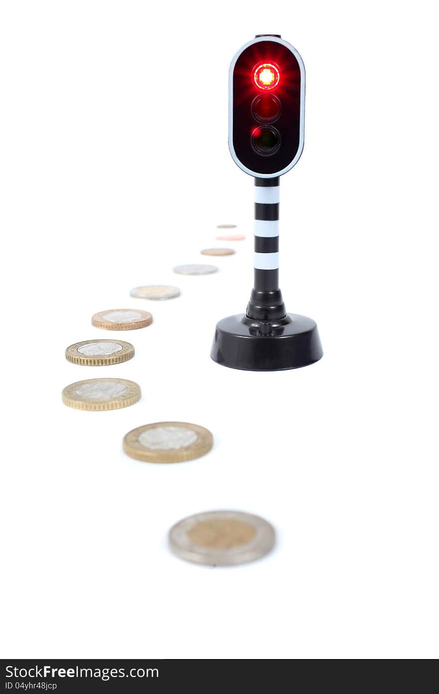 Coins next to a traffic light that has turned red.  Isolated on a white background. Coins next to a traffic light that has turned red.  Isolated on a white background