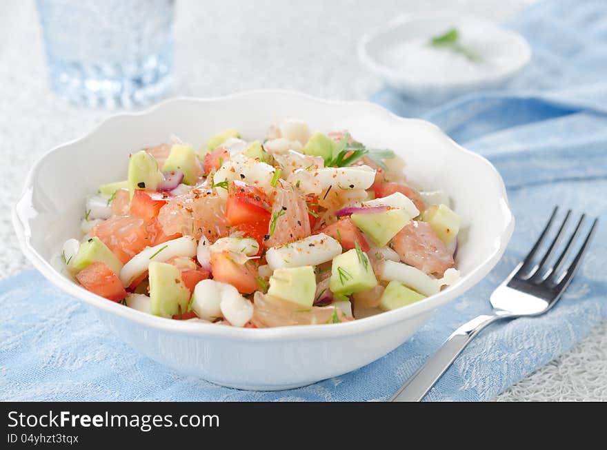 A bowl of salad with squid, avocado and grapefruit, closeup. A bowl of salad with squid, avocado and grapefruit, closeup