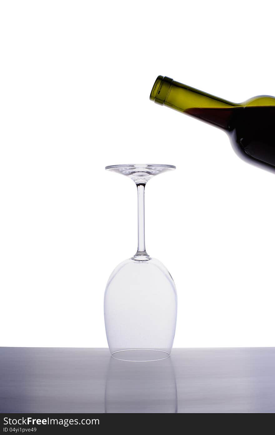 Inverted empty wine glass and bottle of red wine isolated on white background