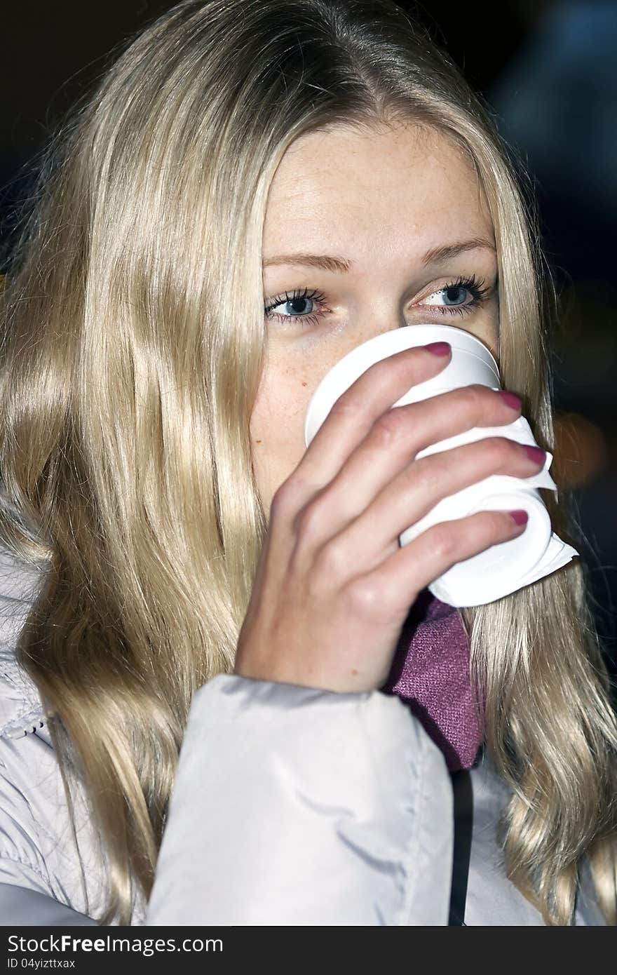 Blue-eyed blonde with long hair drinks from plastic glass. Blue-eyed blonde with long hair drinks from plastic glass