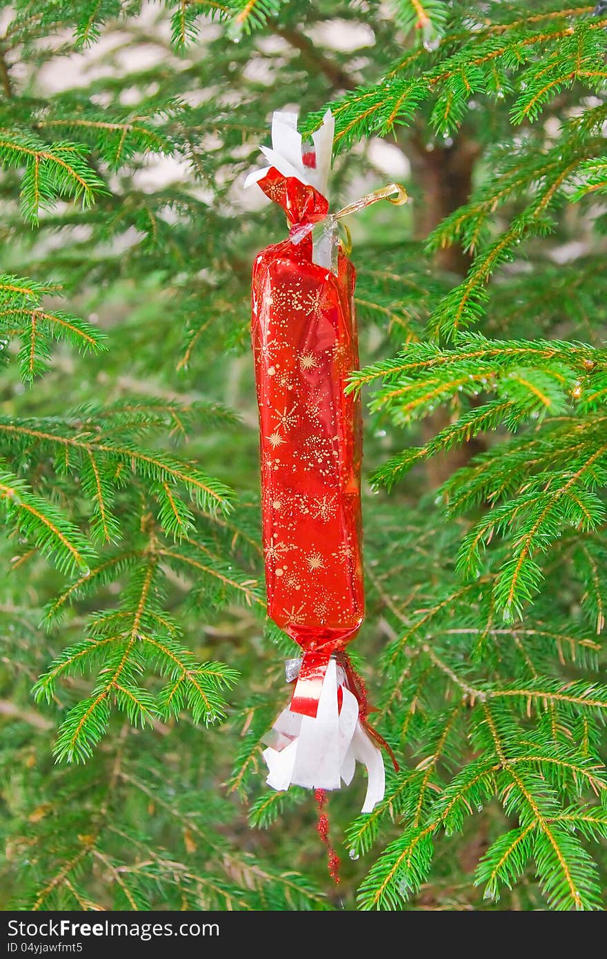 Christmas gift in red wrapping hanging on the Christmas tree