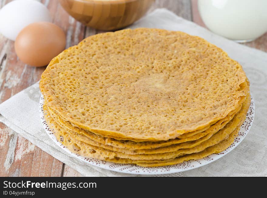 Stack of crepes made ​​of corn flour on a plate and baking ingredients