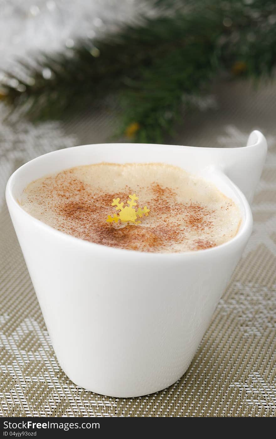 Cup of cappuccino on the table, fir branches in the background