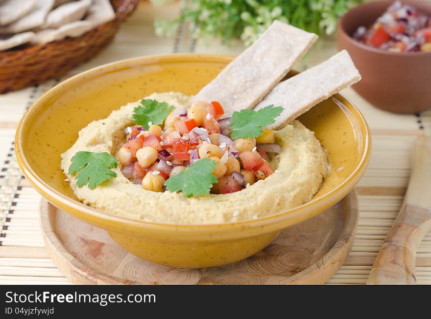 Hummus with a salad of chickpeas and tomatoes with cilantro and crackers closeup