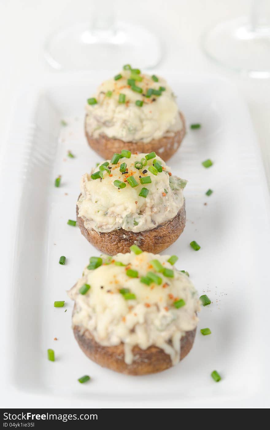 Stuffed mushrooms, baked with cheese and herbs on white dish, selective focus