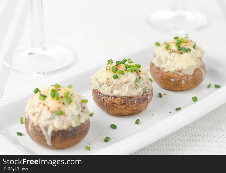 Stuffed mushrooms, baked with cheese and herbs on white dish, selective focus. Stuffed mushrooms, baked with cheese and herbs on white dish, selective focus