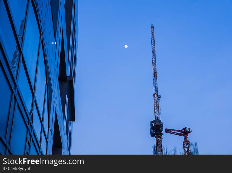 High business building with metal crane and full moon in sky at dawn. High business building with metal crane and full moon in sky at dawn