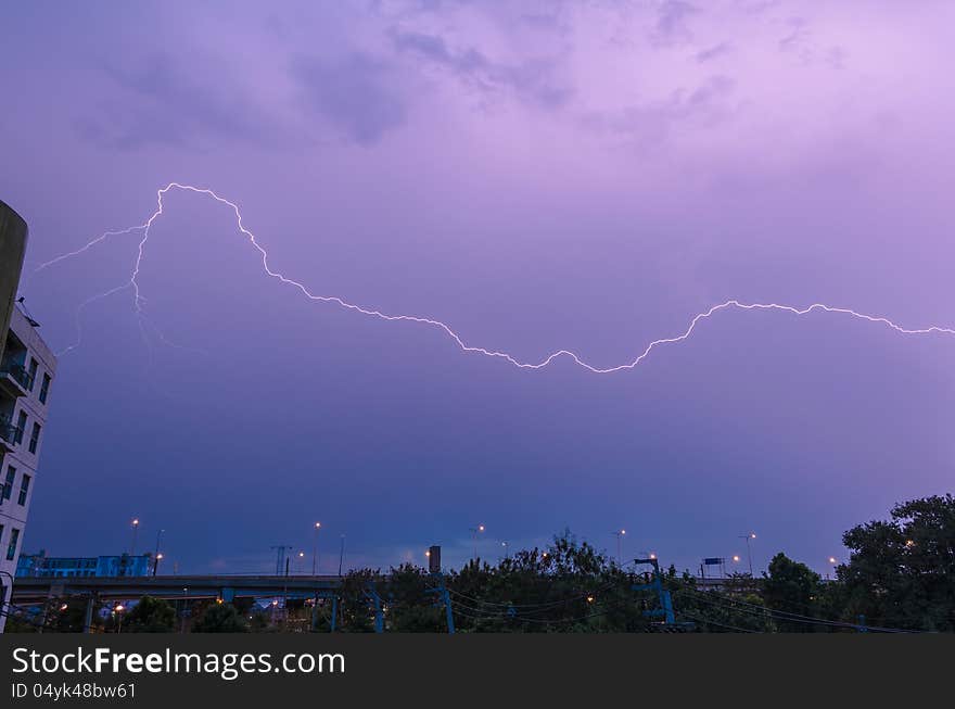 Lightning strike over city sky at twilight