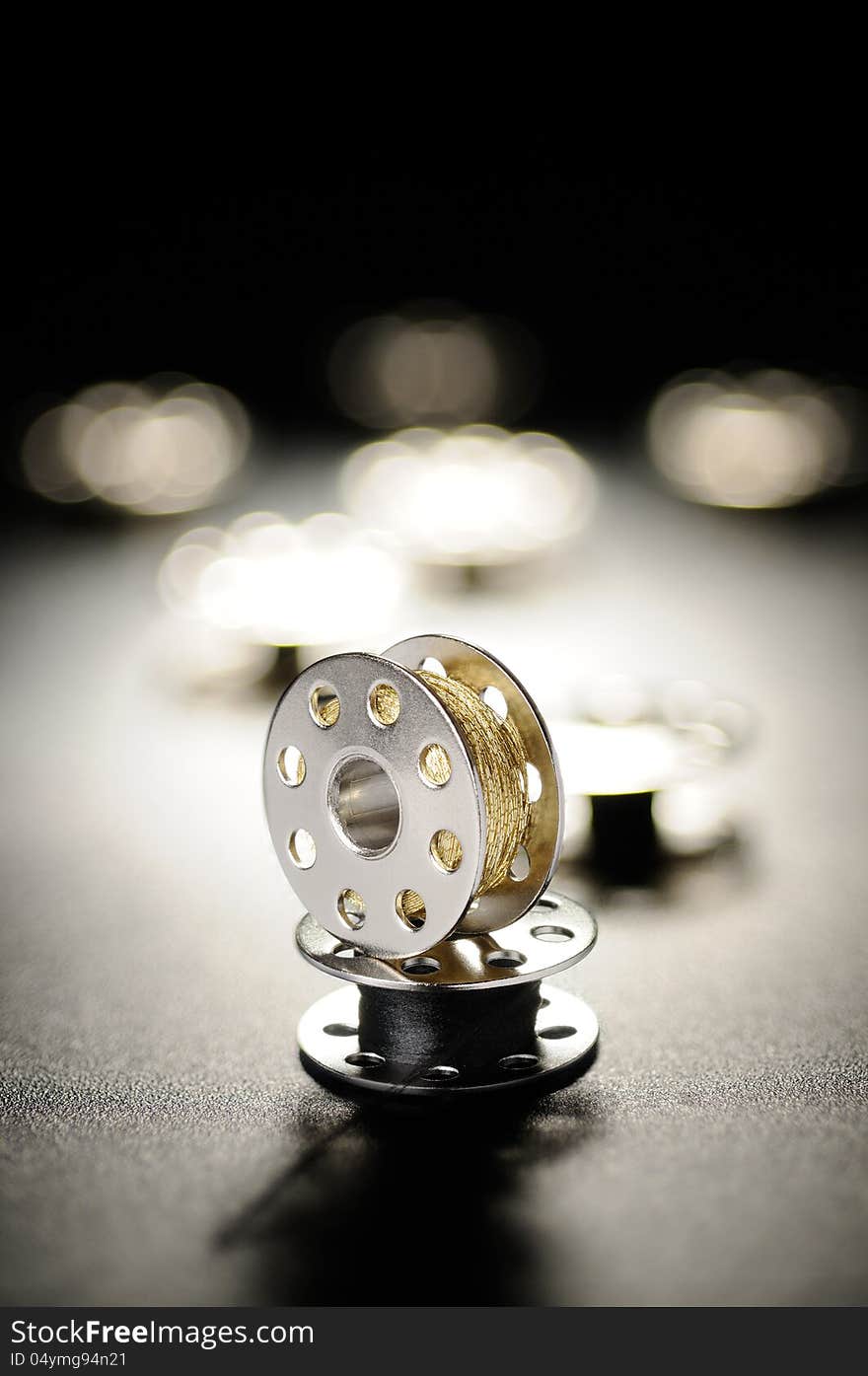 Metal spools of sewing machine on a black background