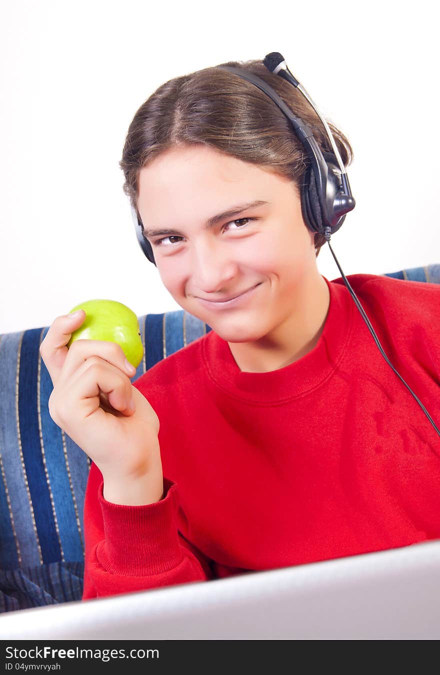 Teenage boy using laptop and eating apple