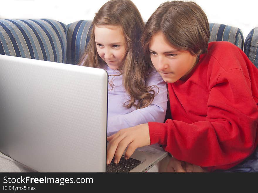 Brother and sister playing games on laptop at home