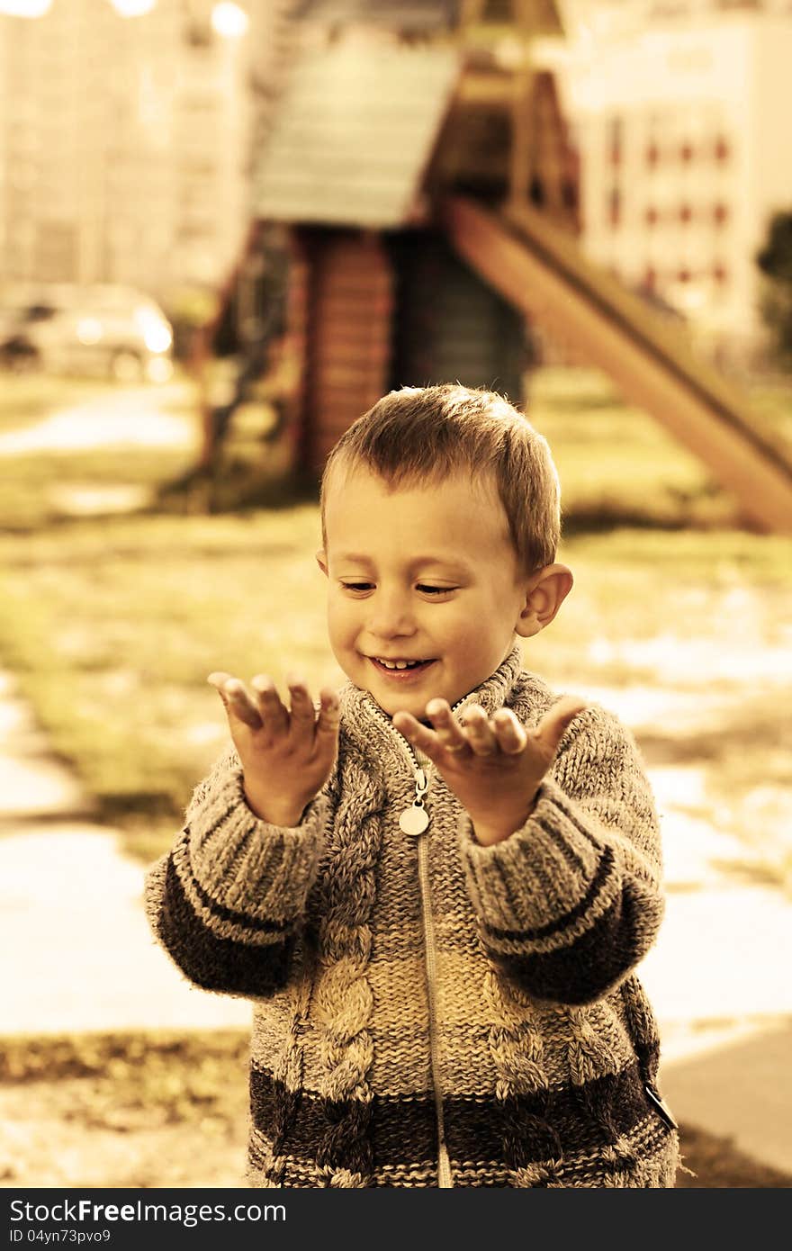 Portrait of the little lovely happy smiling boy looking at his arms. Portrait of the little lovely happy smiling boy looking at his arms