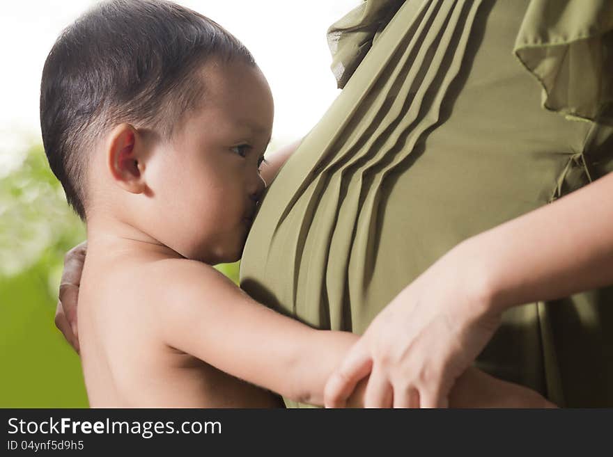 Little boy is kissing the pregnant woman