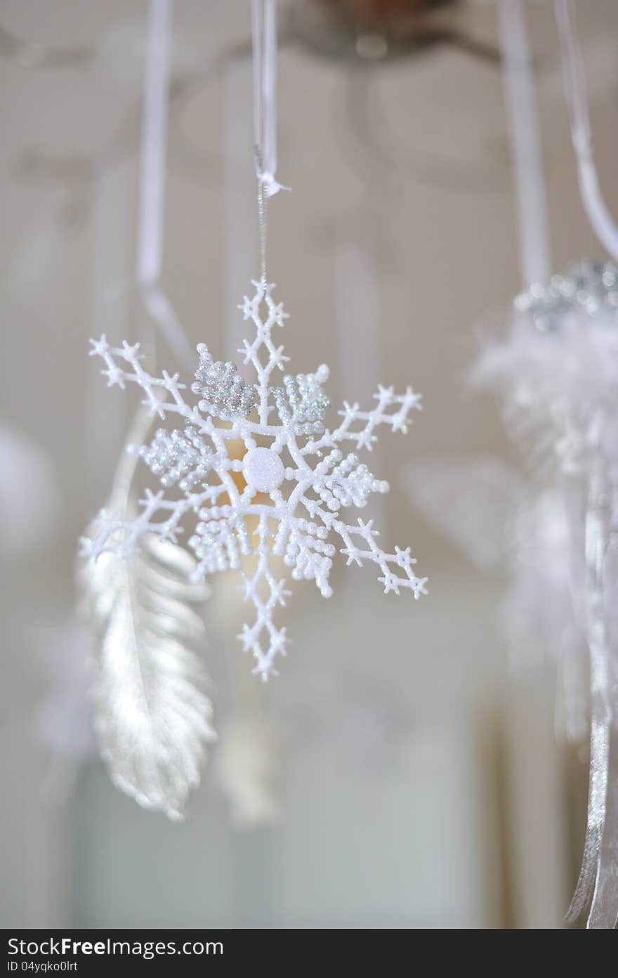 Hanging Christmas decoration snowflake on a background of white feathers. Hanging Christmas decoration snowflake on a background of white feathers