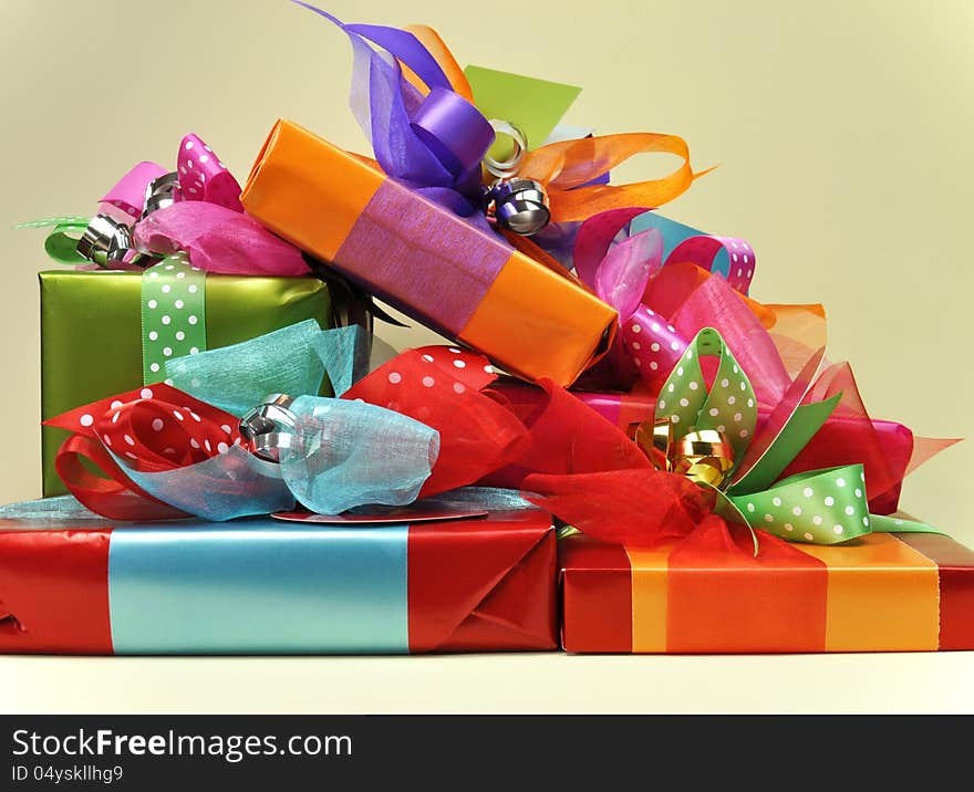 A stack of bright color presents in red, blue, orange, pink and green, with ties, tags and ribbons. A stack of bright color presents in red, blue, orange, pink and green, with ties, tags and ribbons.