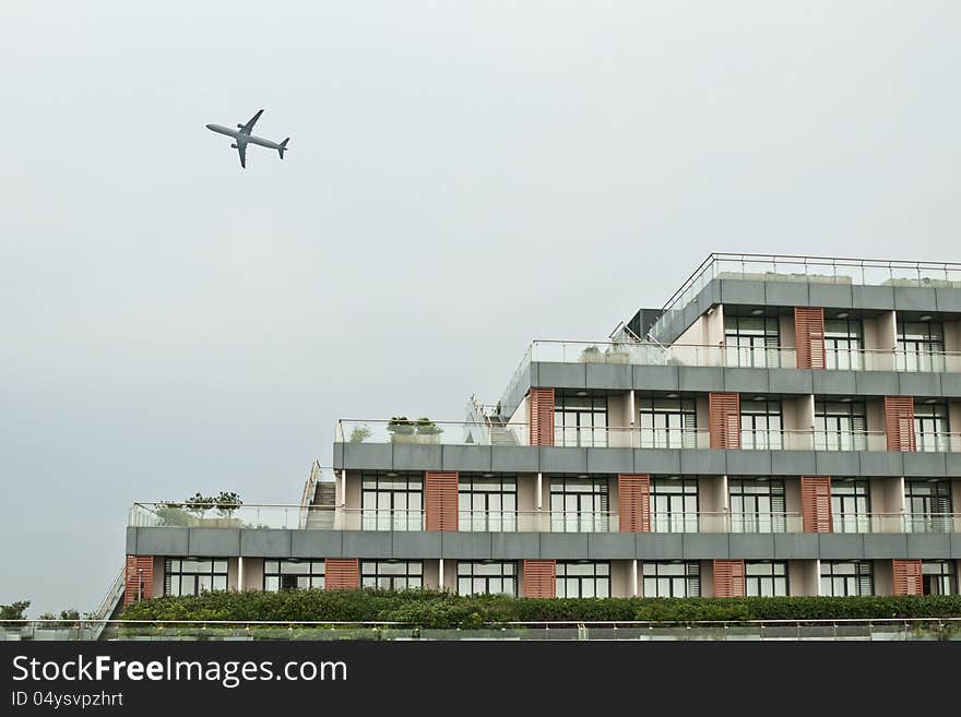 A plane flies through the sky above a building. A plane flies through the sky above a building