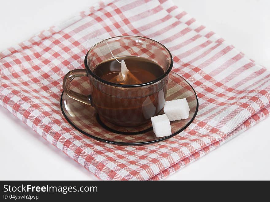 Cup of tea and two slices of sugar on a saucer on a white napkin. Cup of tea and two slices of sugar on a saucer on a white napkin