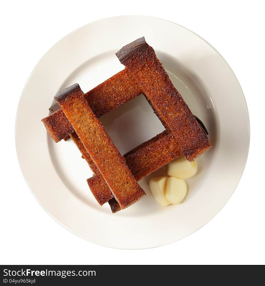 Well-built roasted croutons with garlic on white round dish isolated on a white background. Top view. Well-built roasted croutons with garlic on white round dish isolated on a white background. Top view.