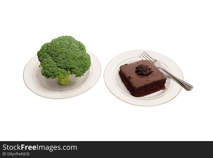 A large stalk of broccoli and a piece of chocolate cake on white plates with a fork.  Gives you a choice of healthy food or unhealthy food. A large stalk of broccoli and a piece of chocolate cake on white plates with a fork.  Gives you a choice of healthy food or unhealthy food.