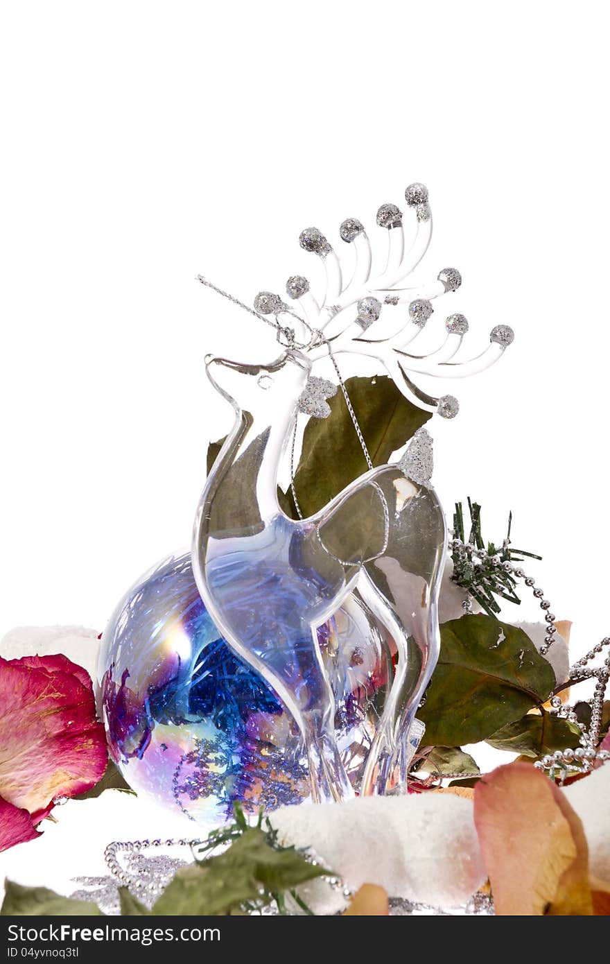 Glass Christmas deer with dry roses leafs and Christmas tinsel on white background.