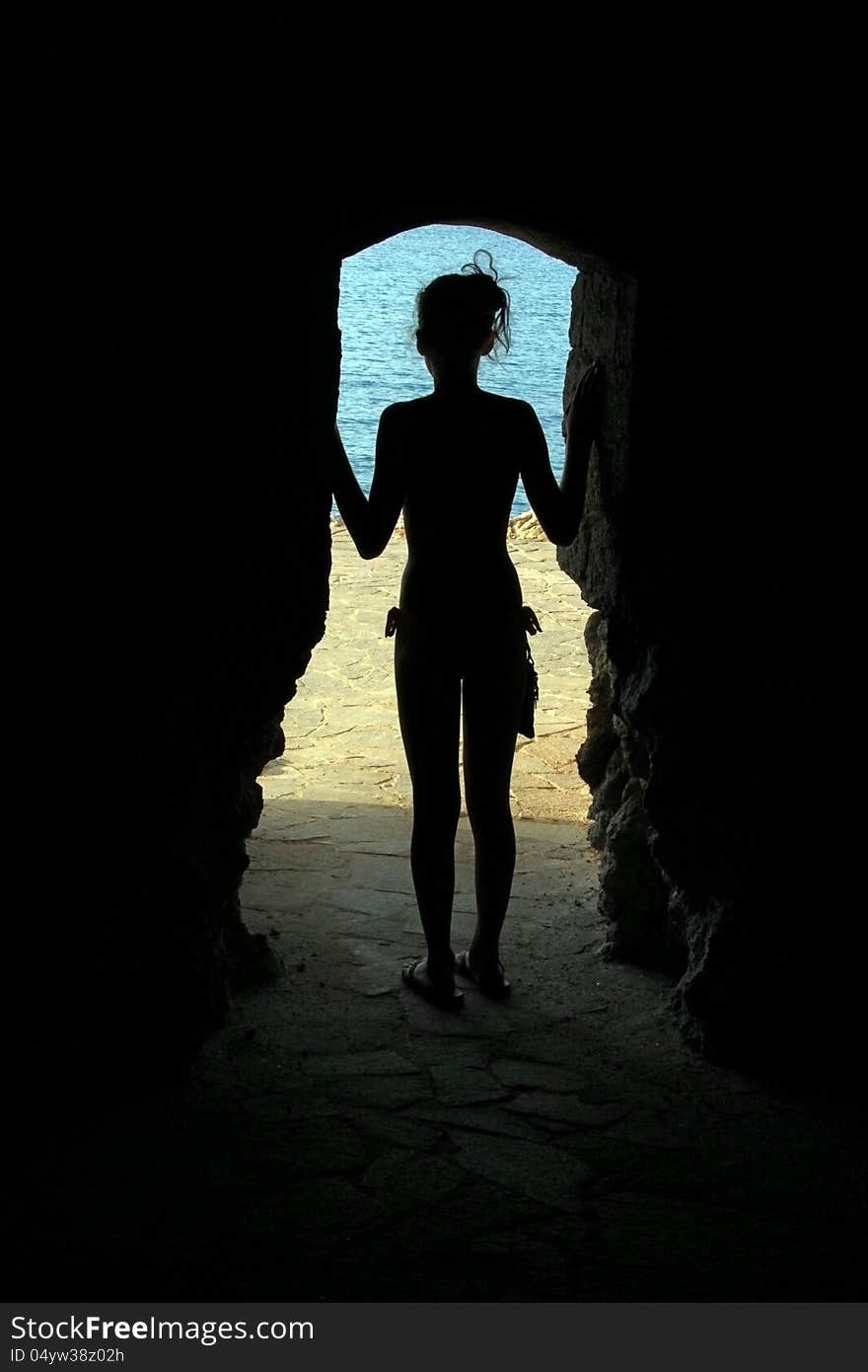 Woman in silhouette with arms wide open at the beach