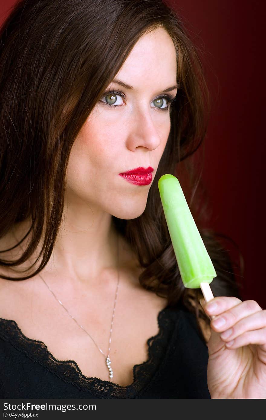 A beautiful brunette has a frozen treat looking off camera. A beautiful brunette has a frozen treat looking off camera