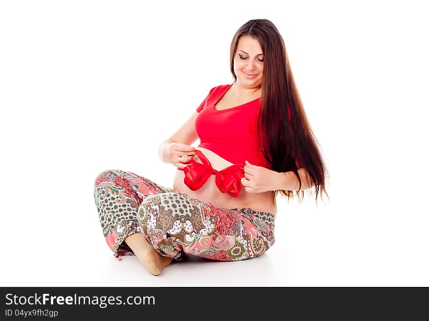 Pregnant girl corrects red bow on her stomach isolated on white background