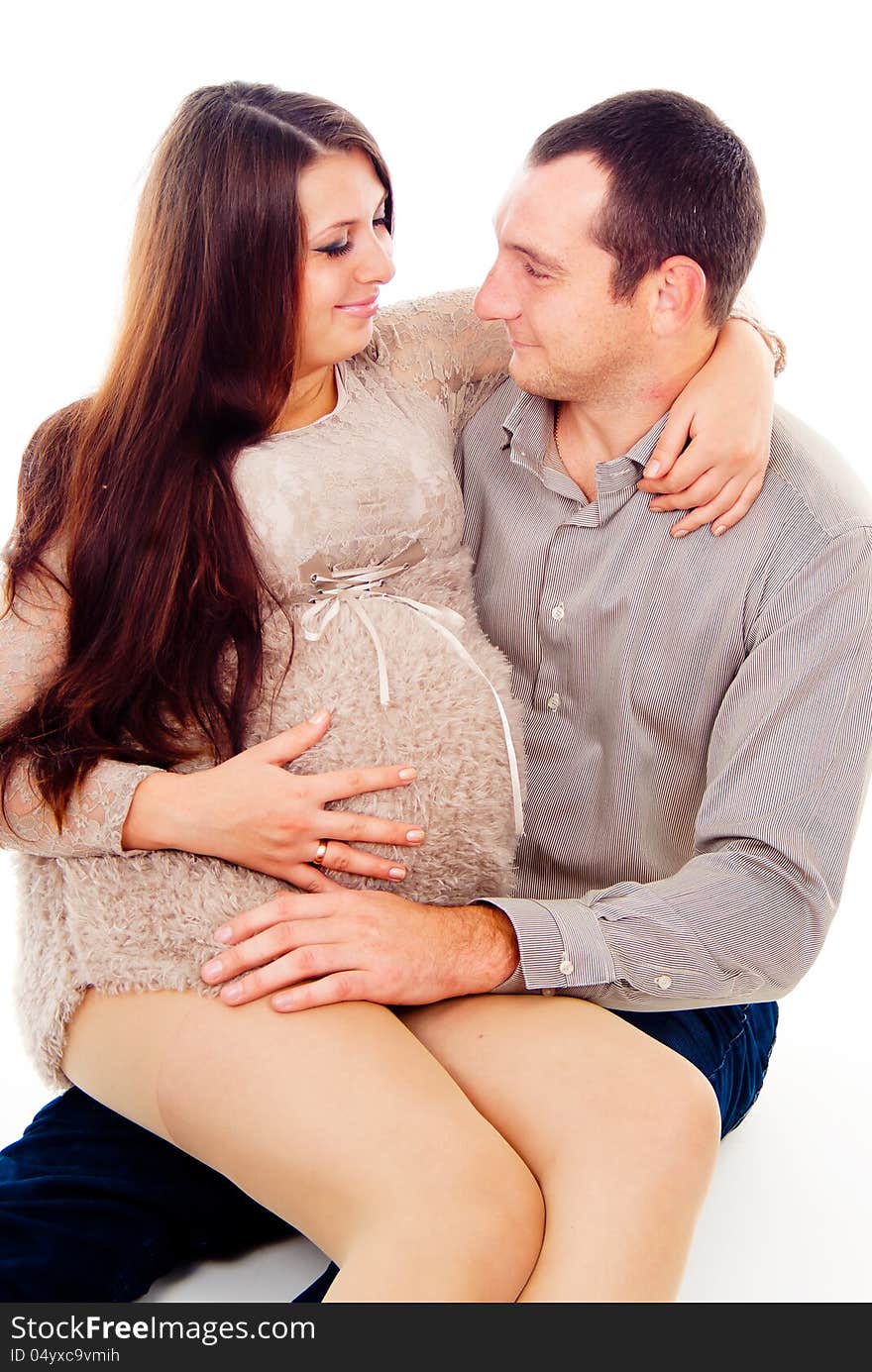 Dad keeps his pregnant wife on her knees on white background