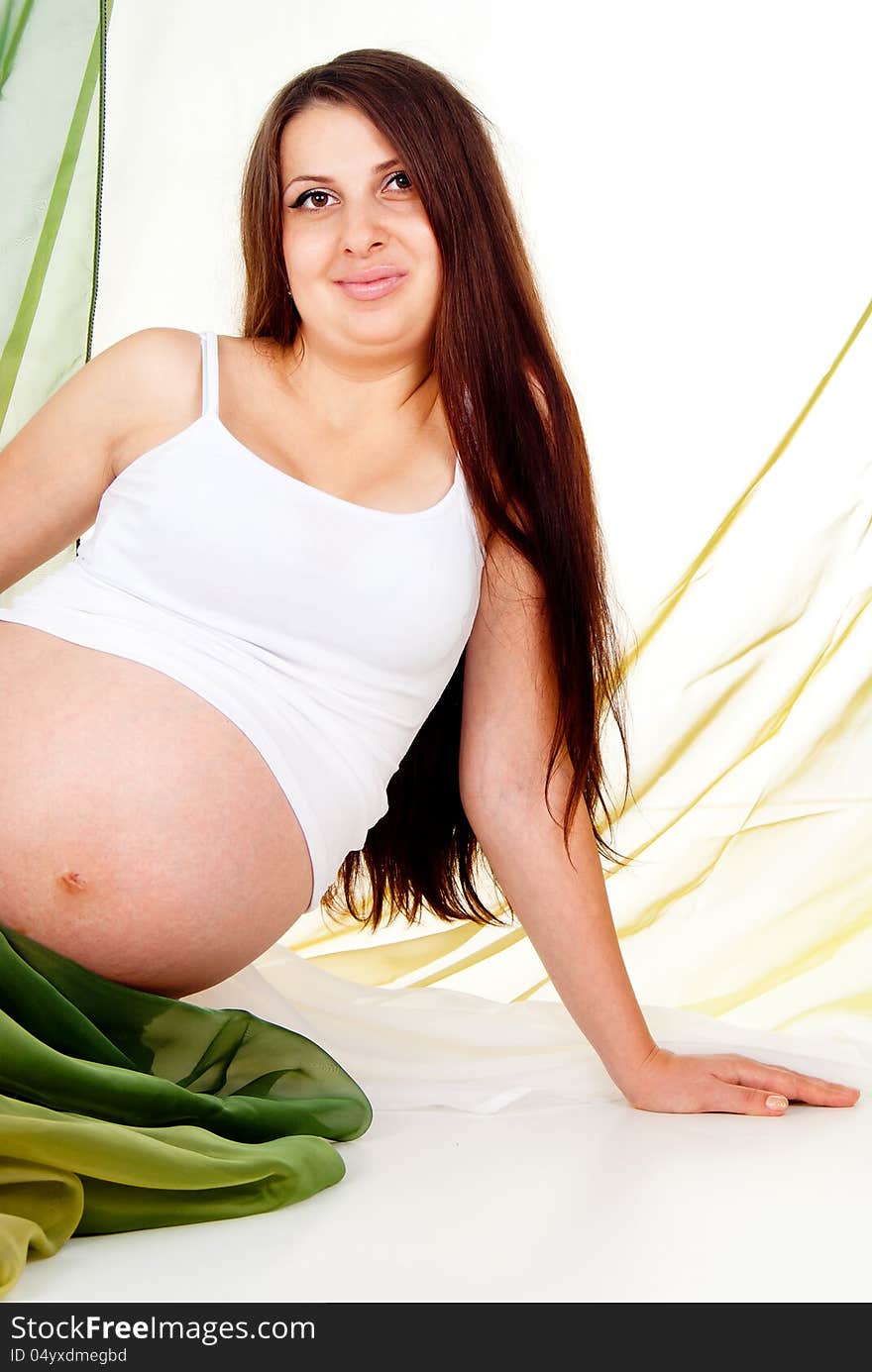 A pregnant girl in a green veil isolated on white background