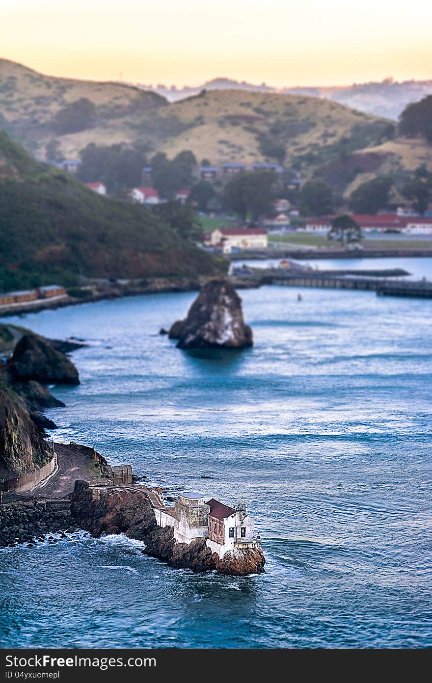 Small house on the rocks in the bay and distant hills