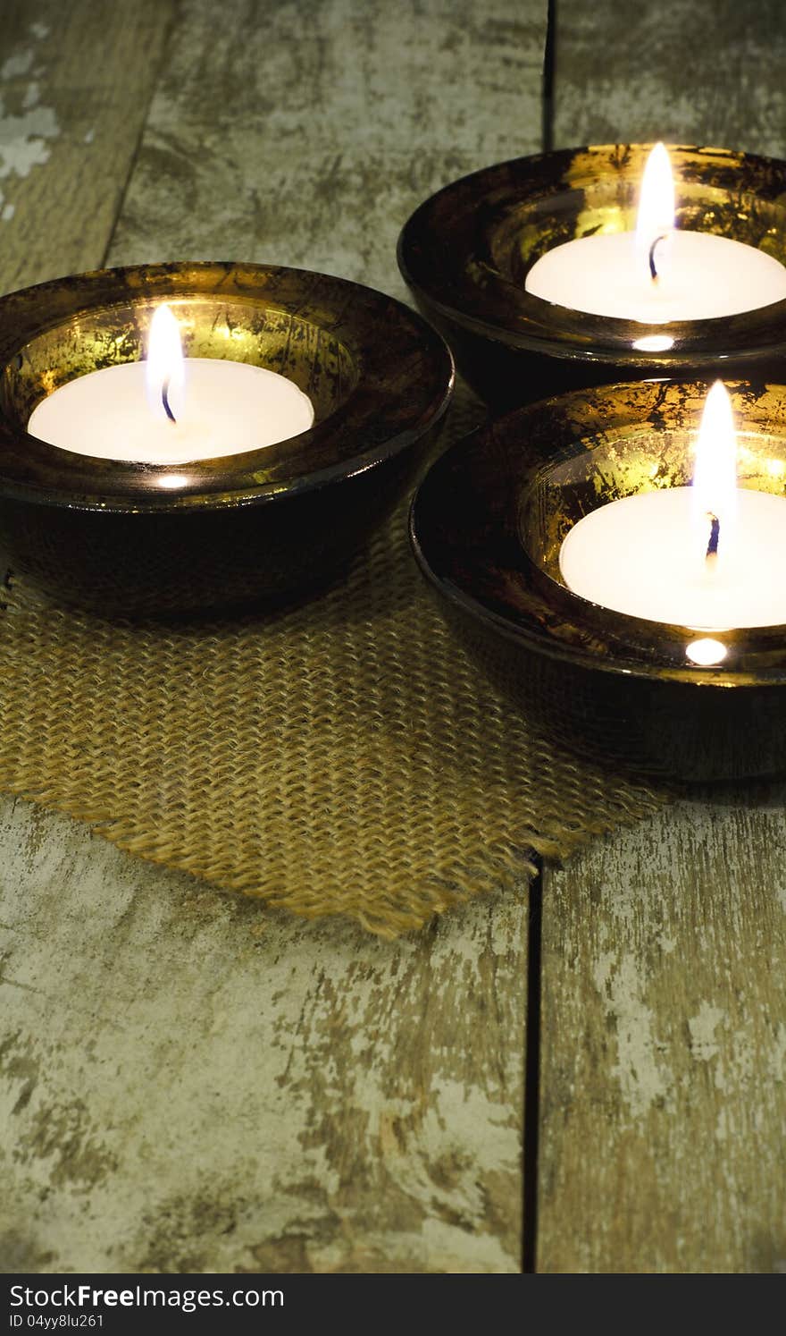 Three black and gold mottled tea light holder on a rustic table. Three black and gold mottled tea light holder on a rustic table