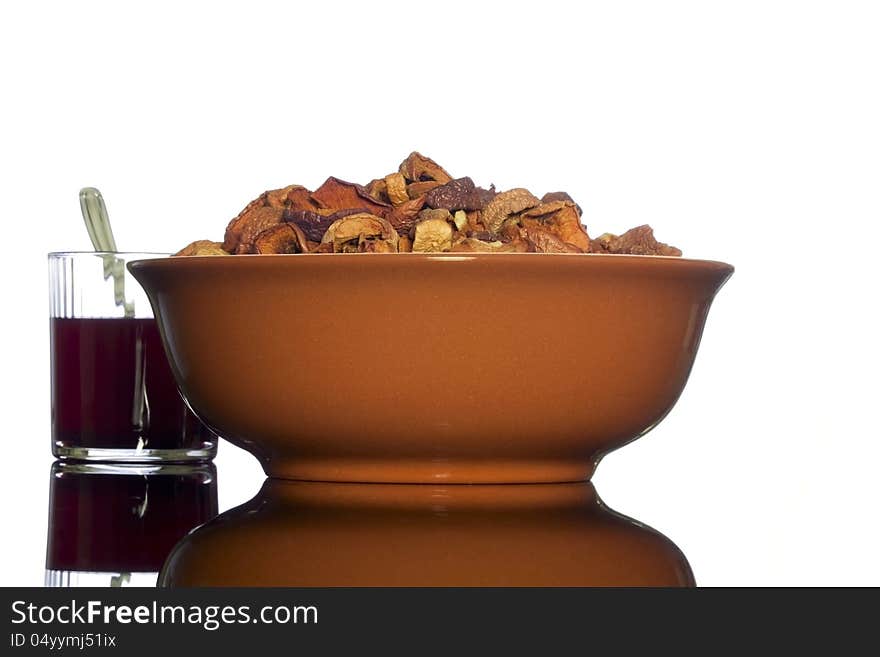 Brown ceramic bowl of homemade dried apples and a glass of transparent glass with a compote of the dried apples   on white background. Brown ceramic bowl of homemade dried apples and a glass of transparent glass with a compote of the dried apples   on white background.