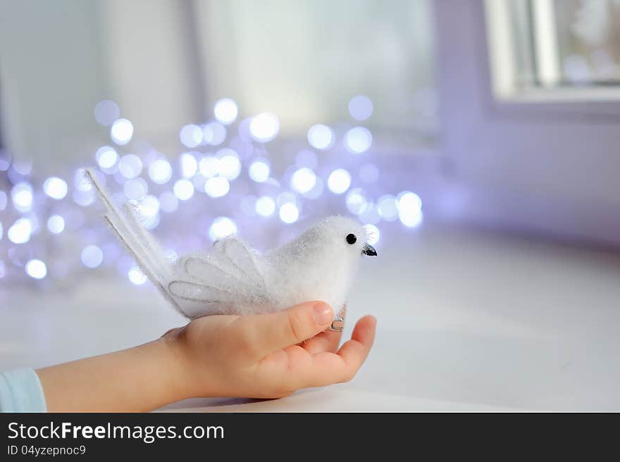 Against the child's hand lights garland with white bird. Against the child's hand lights garland with white bird