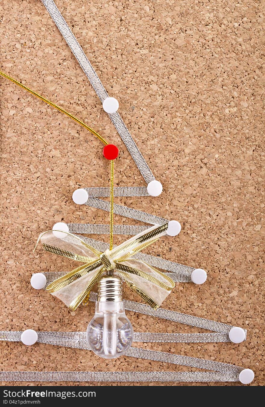 Part of a cork-board  with celebration idea lamp, festive bow and improvised silver Christmas tree on it. Part of a cork-board  with celebration idea lamp, festive bow and improvised silver Christmas tree on it.