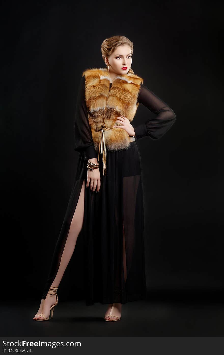 Woman in Fur Coat over Black Background posing