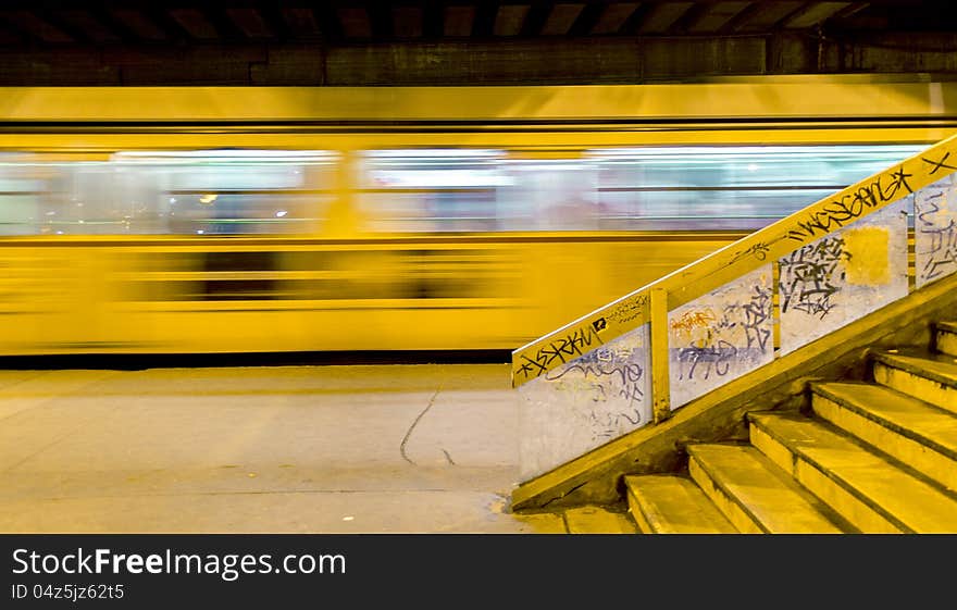 Tram number two runs out from the stop, under a bridge. On the right side there are the stairs to the bridge, decorated with graffties. Tram number two runs out from the stop, under a bridge. On the right side there are the stairs to the bridge, decorated with graffties