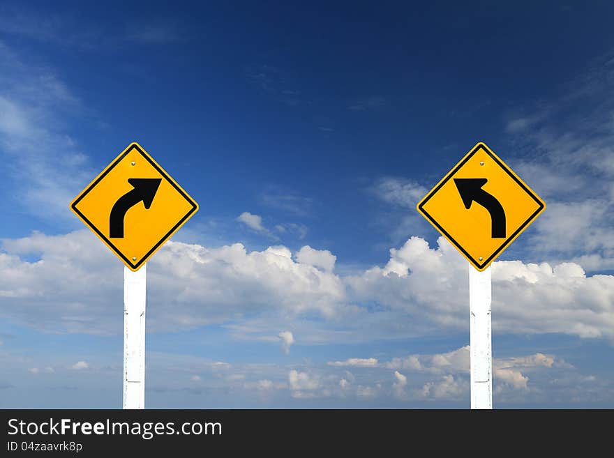 Direction sign- left and right turn warning on blue sky background with blank for text. Direction sign- left and right turn warning on blue sky background with blank for text