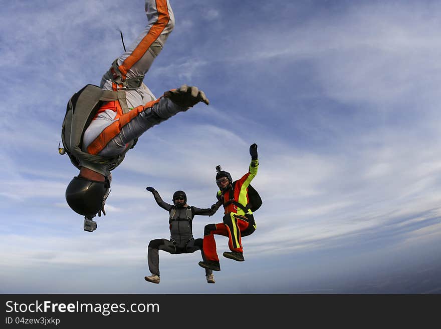 Three parachutists perform freestyle figures in free fall. Three parachutists perform freestyle figures in free fall.