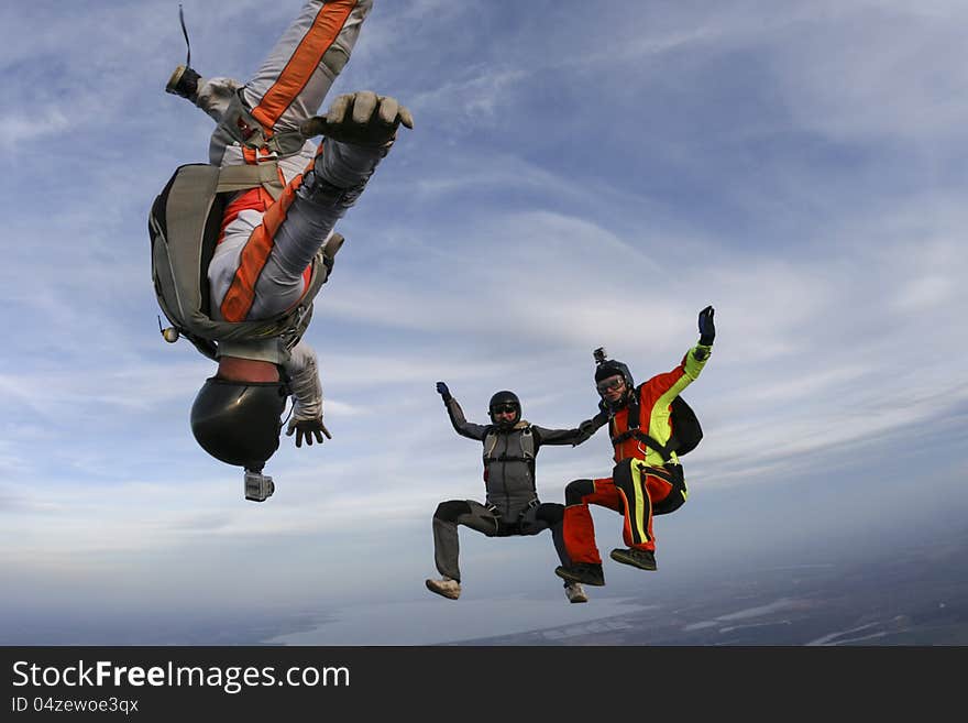 Three parachutists perform freestyle figures in free fall. Three parachutists perform freestyle figures in free fall.