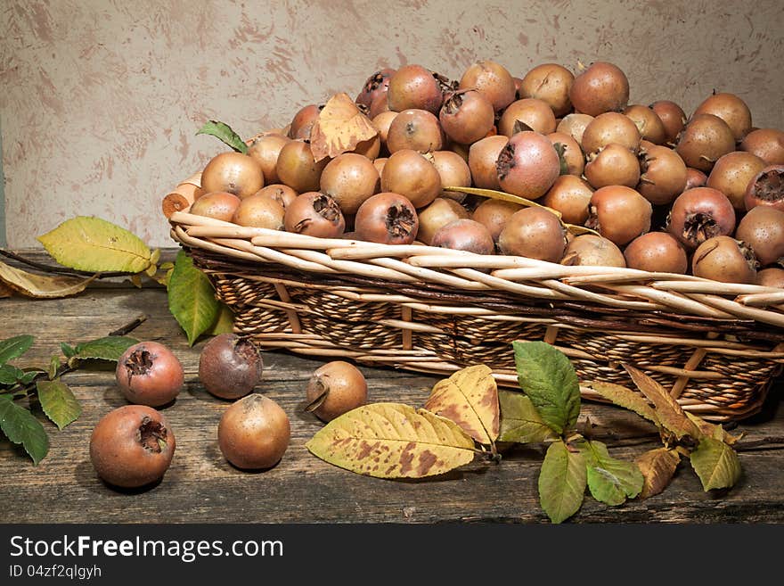 A basket of Medlars, above a wooden table