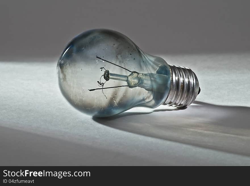 Incandescent bulb after. a tungsten filament burns out: dirty glass with blue coating, carbon black, jagged spiral and protruding wires. Incandescent bulb after. a tungsten filament burns out: dirty glass with blue coating, carbon black, jagged spiral and protruding wires.