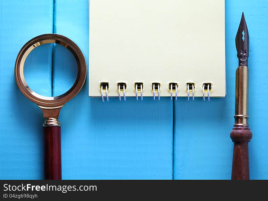 Notebook on the wood with pocket watch and magnifying glass