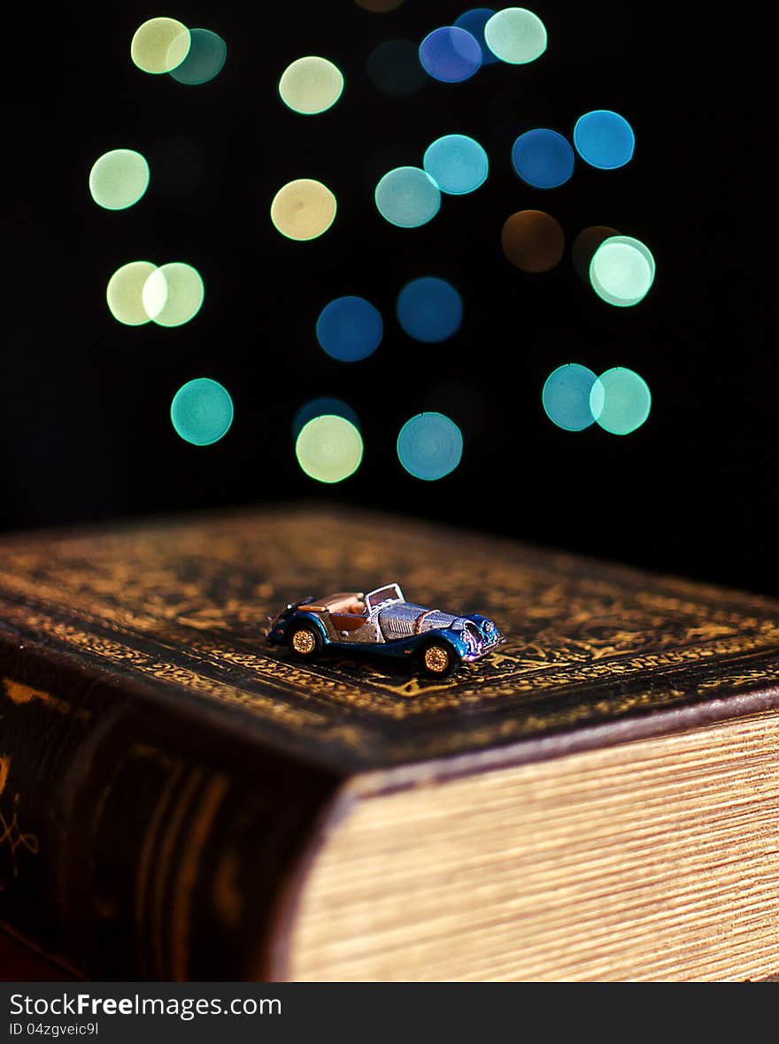 Old book and miniature car on bokeh lights background